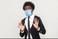 No, wait, stop please. Portrait of shocked or scared young man in black suit with medical mask standing with blocking hands and