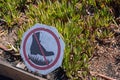 No walking boot cross out sign in front of garden with plants growing