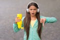 No water no life. Concerned child show thumbs down hand gesture. No water left in bottle. Thirsty girl wear headphones