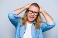 No way! Close up portrait of very upset, unhappy men in glasses, jeans shirt holding hands on head, looking at camera over grey b Royalty Free Stock Photo