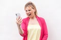 No way! Portrait of angry bossy young woman in pink blouse standing and watching on her cellphone with aggressive face