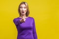 No way, that`s you! Portrait of wondered woman in tight purple dress pointing at camera. on yellow background