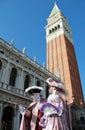 Noble masked couple under Bell tower of San Marco