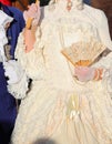 noblewoman with ivory white historical dress and a fan in gloved hand during party in Venice Italy