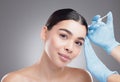 Nobodys perfect. Studio portrait of an attractive young woman having some plastic surgery done against a grey background