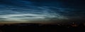 Noctilucent mesospheric clouds in night sky. Rare atmospheric phenomenon over city.