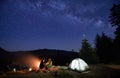 Night camping in mountains near forest with campfire and tourist tent. Royalty Free Stock Photo