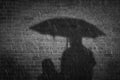 Noir style autumn rainy night in city. Mother with children in rain protected with umbrella. Two people cast a shadow on