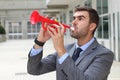 Noisy businessman playing a plastic trumpet