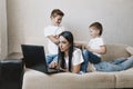 Noisy children distract mothers from working at the computer. annoyed mom holds her head