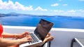 Nomad digital with laptop and running remotely with bright scenic view of the Mediterran ean Sea and Santorini caldera -work