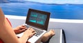 Nomad digital with laptop and running remotely with bright scenic view of the Mediterranean Sea and Santorini caldera -work