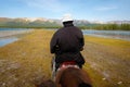 Nomadic man riding horse on the shore of the lake KhÃÂ¶vsgÃÂ¶l, blue sky with the clouds in the horizon. Horseman walking wild