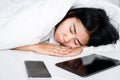 Nomophobia concept Asian woman sleeping with mobile phone and tablet in bed, internet, technology addiction