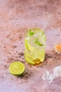 Non-alcoholic soft drink with lime slices, ice cubes and fresh mint in a jar-shaped glass on a brown background Royalty Free Stock Photo