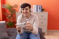 Non binary man smiling confident playing video game at home Royalty Free Stock Photo