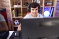 Non binary man streamer playing video game using computer at gaming room Royalty Free Stock Photo