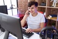 Non binary man streamer talking on smartphone using computer at gaming room