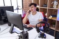 Non binary man streamer talking on smartphone using computer at gaming room