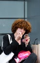 non-binary person applies lipstick sitting on a bench