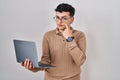 Non binary person using computer laptop pointing to the eye watching you gesture, suspicious expression Royalty Free Stock Photo