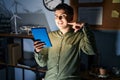 Non binary person using touchpad device at night smiling cheerful showing and pointing with fingers teeth and mouth Royalty Free Stock Photo
