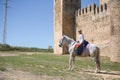 Non-binary person, young and South American, very makeup, mounted on a white horse, with a gay pride flag on the rump, next to an Royalty Free Stock Photo