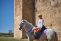 Non-binary person, young and South American, very makeup, mounted on a white horse, with a gay pride flag on the rump, next to an Royalty Free Stock Photo