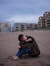 non binary young woman alone on the beach sitting on the sand