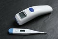 Non-contact infrared and digital thermometers on slate background