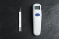 Non-contact infrared and mercury thermometers on slate background, flat lay