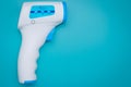 Non-contact infrared thermometer for measuring temperature from a distance on blue background. Device. Thermal radiation thermomet