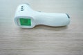 Non-contact infrared thermometer is the wooden table. On the green screen the figure numeral is 36.6