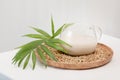 Glass cup of plant milk with palm leaf on a wooden plate with buckwheat groats