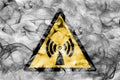 Non ionising electromagnetic radiation hazard warning smoke sign. Triangular warning hazard sign, smoke background. Royalty Free Stock Photo