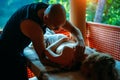 Non-traditional wellness massage outdoor. Young slender masseur massages a woman`s shoulder, hand and shoulder blade