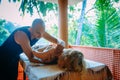 Non-traditional wellness massage outdoor. Young slender masseur massages a woman`s shoulder, hand and shoulder blade