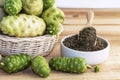 Noni fruit in basket with noni powder in ceramic bowl and wooden