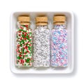 Nonpareils, colored tiny sugar balls, in glass bottles in a white bowl