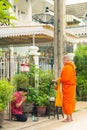 Asian woman is sitting and respecting Buddhist monks after offering food to monks, at front home in the morning, Monk wearing a Royalty Free Stock Photo