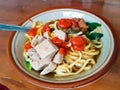 Noodle with chicken in bowl on wooden background with chicken strip, vegetable, meet ball, and chili sauce. Mie Ayam bakso