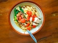 Noodle with chicken in bowl on wooden background with chicken strip, vegetable, meet ball, and chili sauce. Mie Ayam bakso