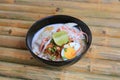 Noodle in coconut milk soup in bowl on bamboo wood table. Fusion Thai food