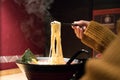 Noodle ramen on chopstick hold on women hand, food and drink concept with copy space