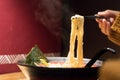 Noodle ramen on chopstick hold on women hand, food and drink concept with copy space