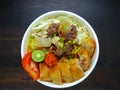 Noodle Soto Bogor with meat and vegetable in white bowl on wooden table indonesian traditional food