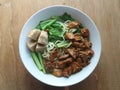 Noodle soup topped with chicken in small slices and mustard greens. Wooden background Royalty Free Stock Photo