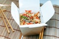 Noodles with chicken, sesame seeds and vegetables in take-out box on wooden table Royalty Free Stock Photo