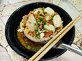 Noodles with Meatballs and pork with various seasonings placed in a black cup served with wooden chopsticks