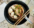 Noodles with Meatballs and pork with various seasonings placed in a black cup served with wooden chopsticks